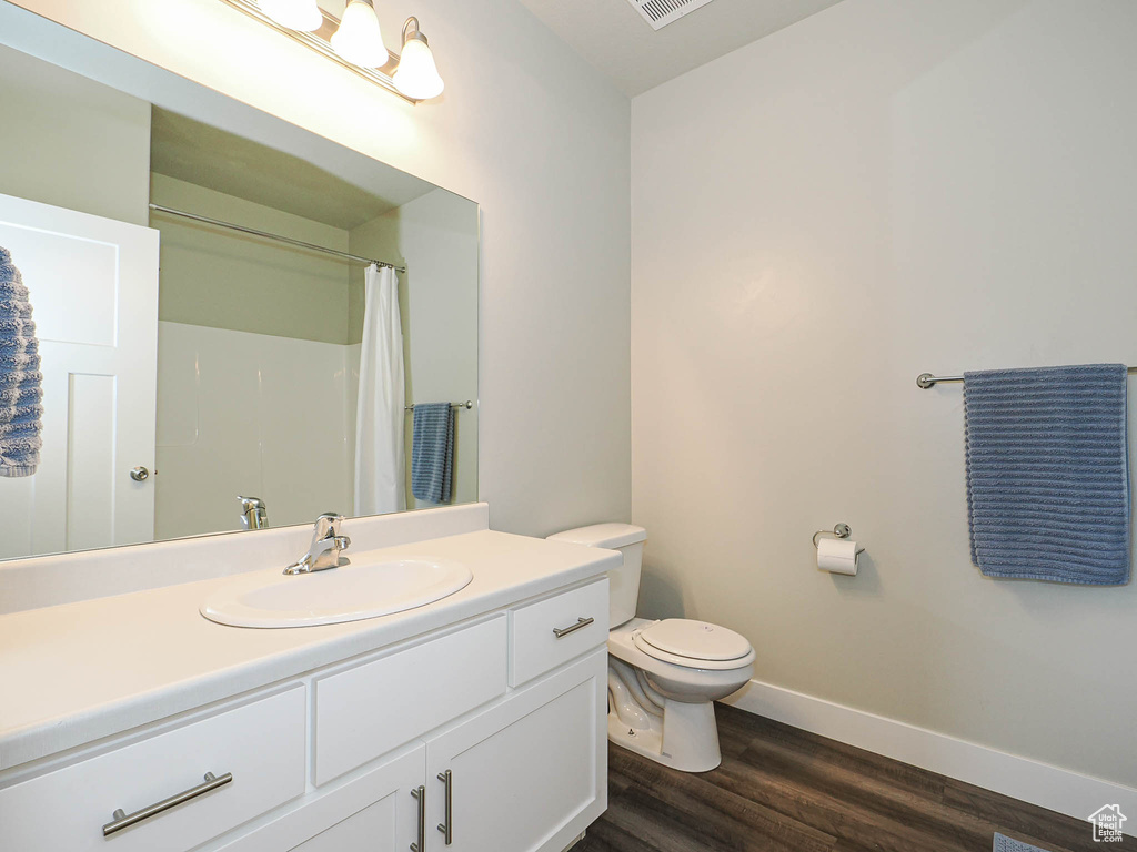Bathroom with wood finished floors, vanity, baseboards, toilet, and a shower with shower curtain