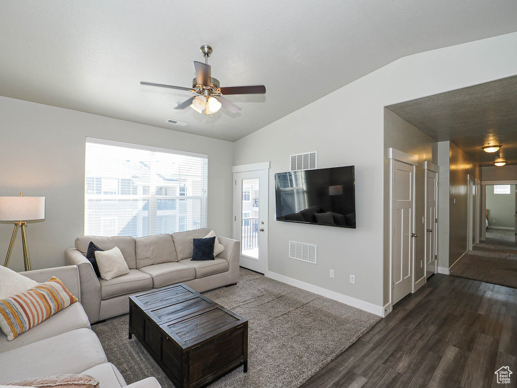 Living room featuring lofted ceiling, dark wood-style floors, a ceiling fan, healthy amount of natural light, and baseboards