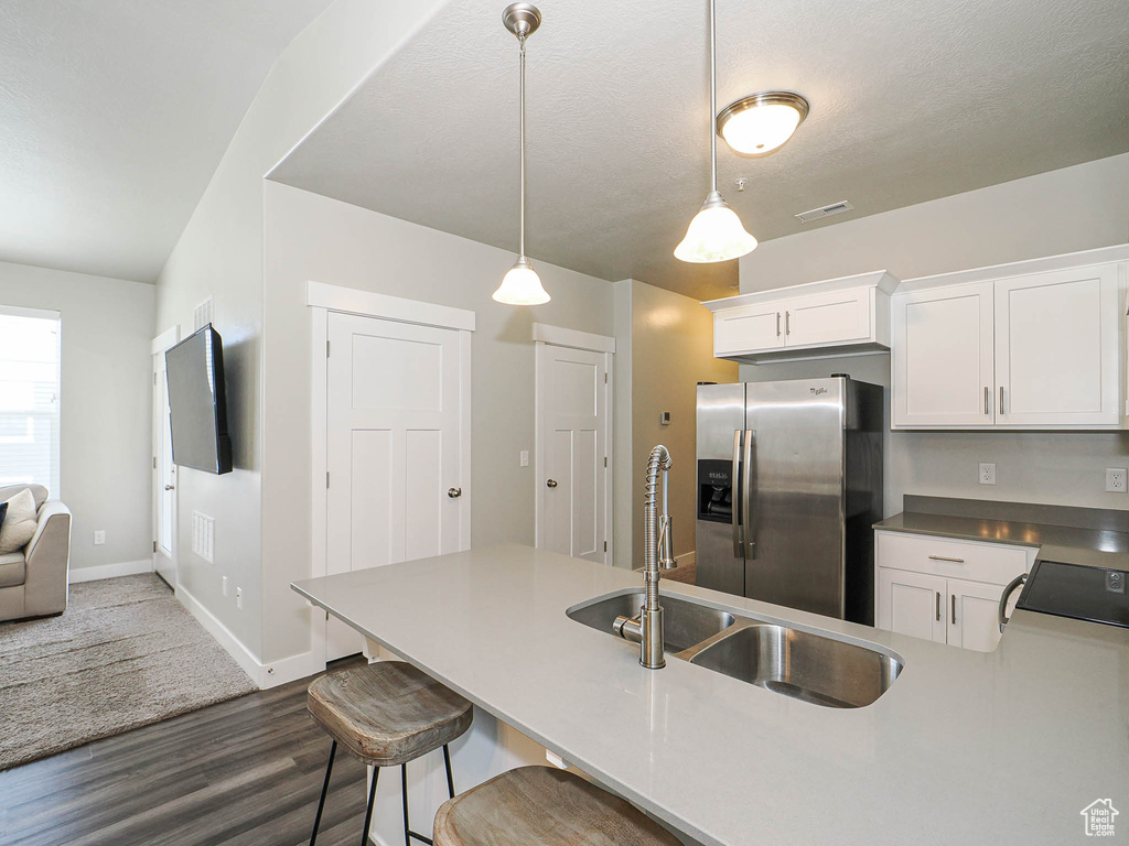 Kitchen featuring stainless steel fridge, dark wood-type flooring, and white cabinets