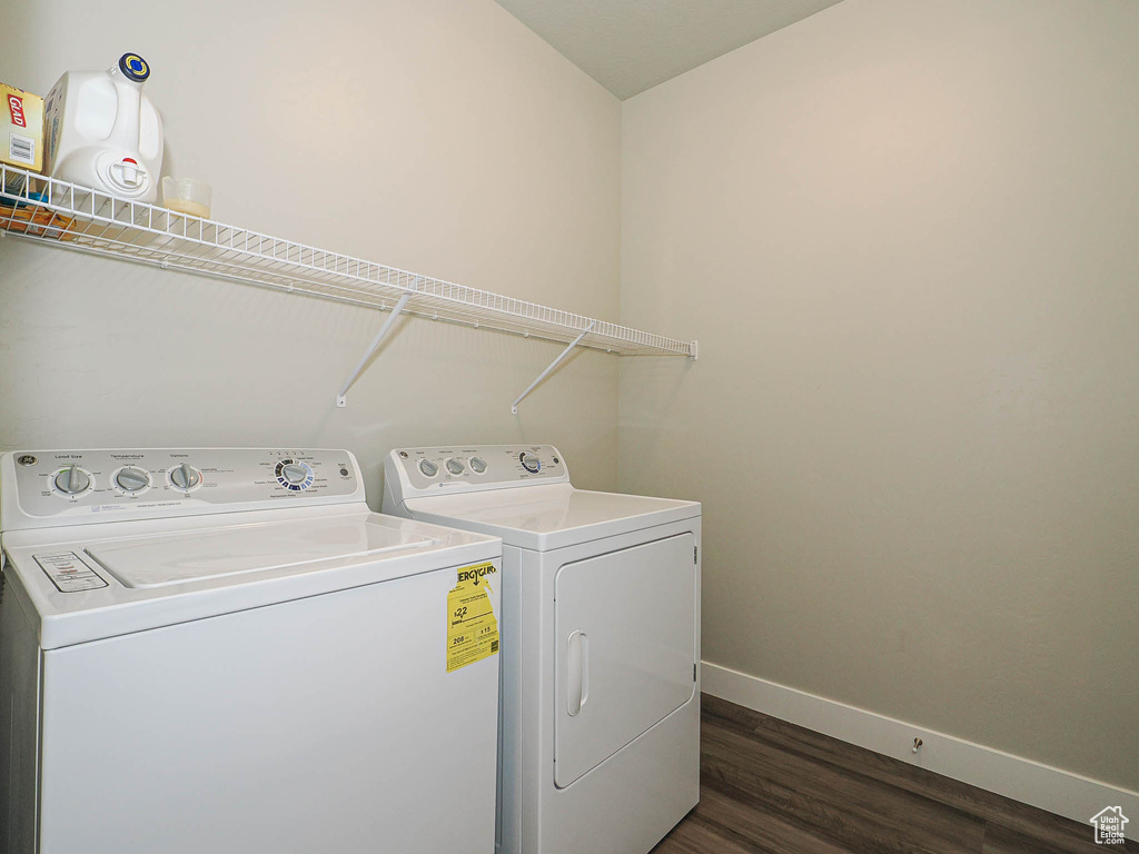 Washroom with baseboards, washing machine and clothes dryer, and dark wood-style flooring
