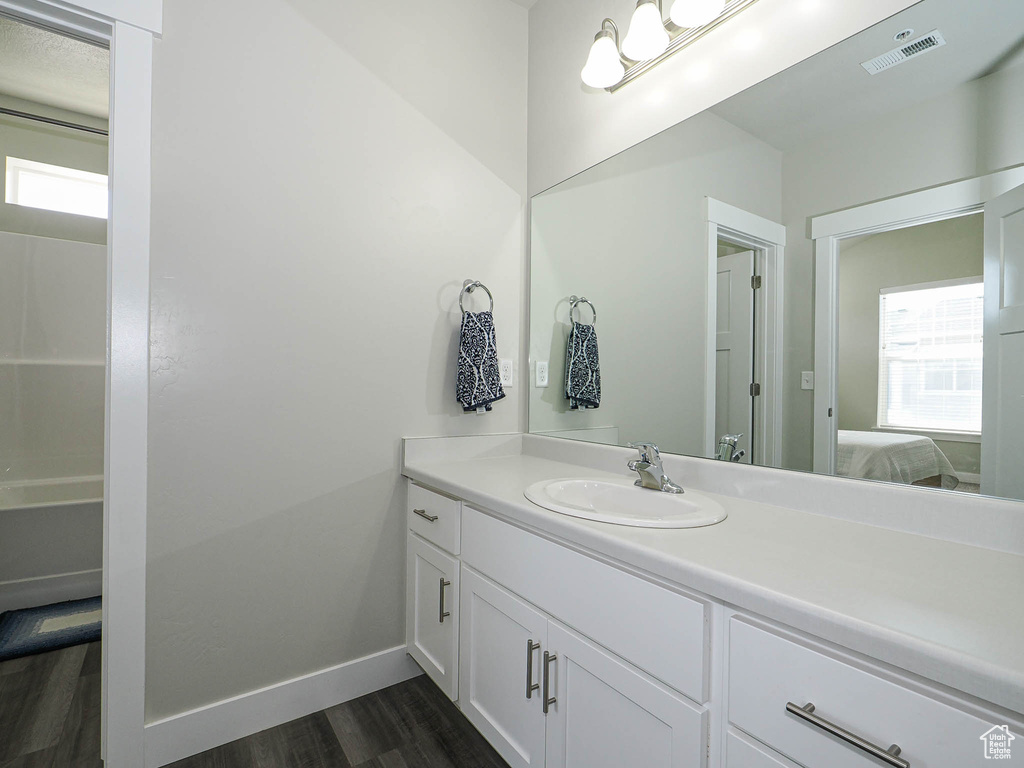 Full bathroom featuring vanity, wood finished floors, baseboards, and ensuite bath