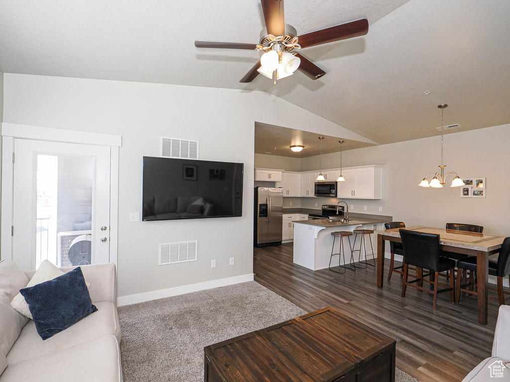 Living room with a chandelier, vaulted ceiling, ceiling fan, and baseboards
