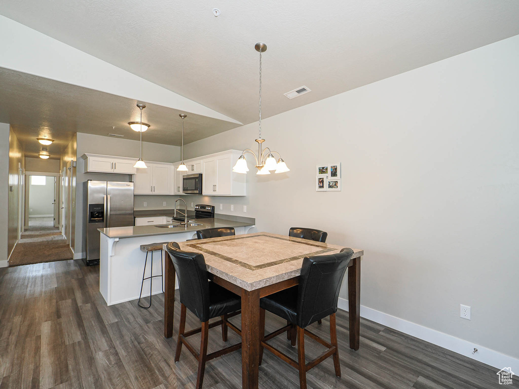 Dining space with dark wood-style flooring, lofted ceiling, a chandelier, and baseboards