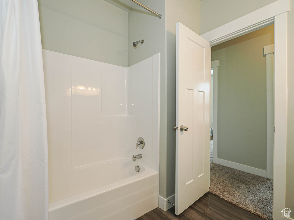 Full bath with shower / tub combo with curtain, wood finished floors, and baseboards