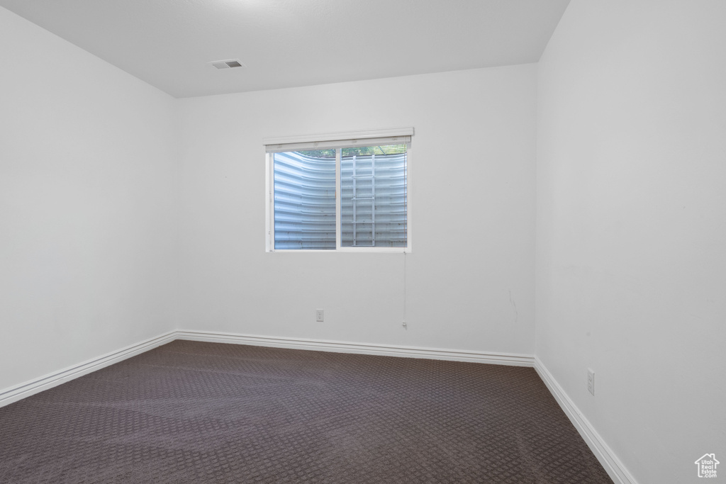 Unfurnished room with dark carpet and baseboards