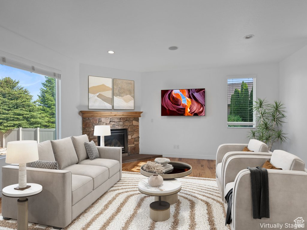 Living room featuring healthy amount of natural light, wood finished floors, a stone fireplace, baseboards, and recessed lighting