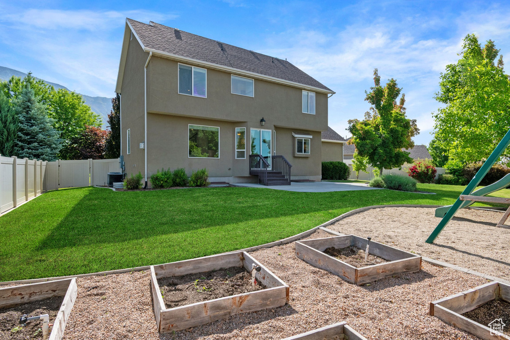 Back of house featuring a vegetable garden, stucco siding, and central air condition unit