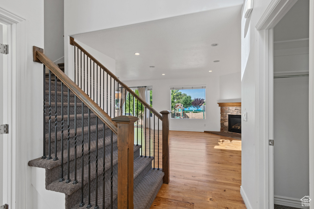 Staircase with wood finished floors, recessed lighting, a fireplace, and baseboards