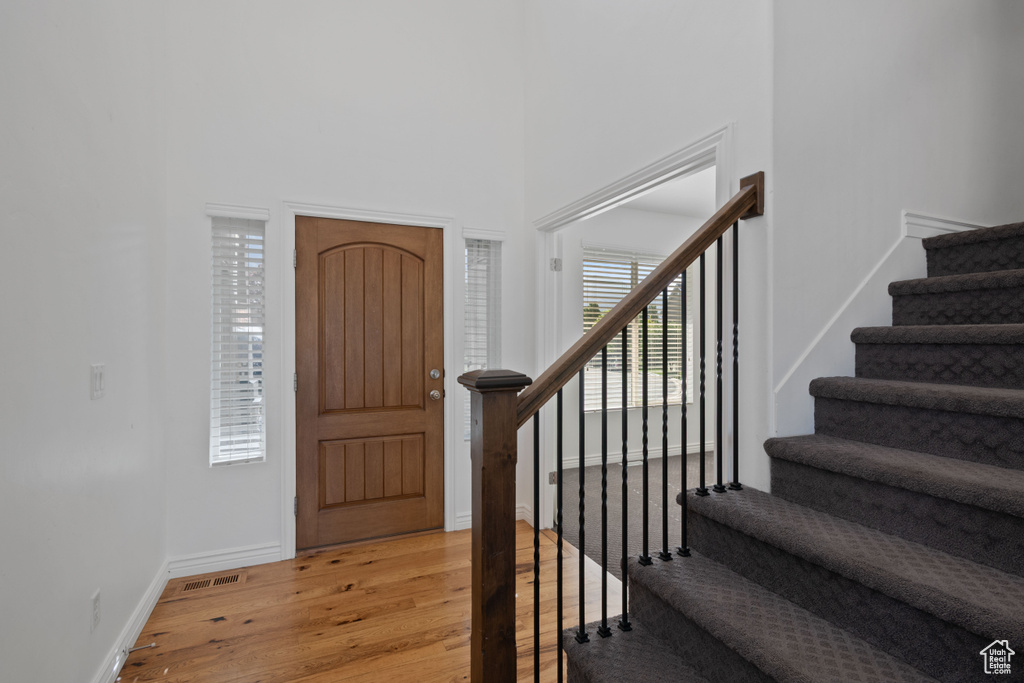 Foyer featuring light wood-type flooring, stairs, baseboards, and a towering ceiling