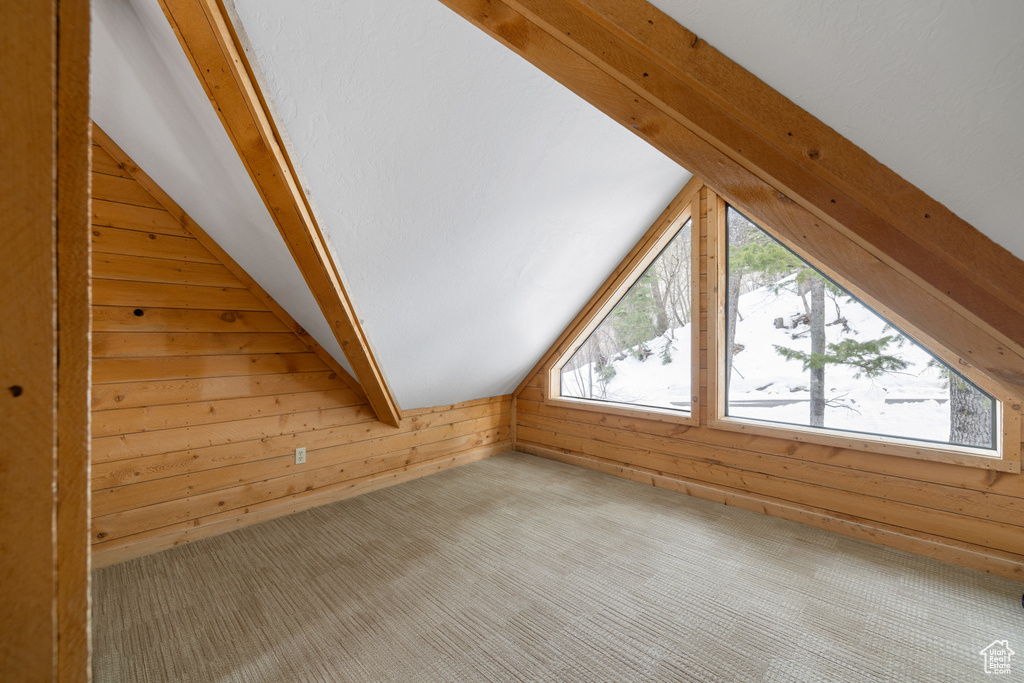 Bonus room with wood walls, lofted ceiling, and carpet