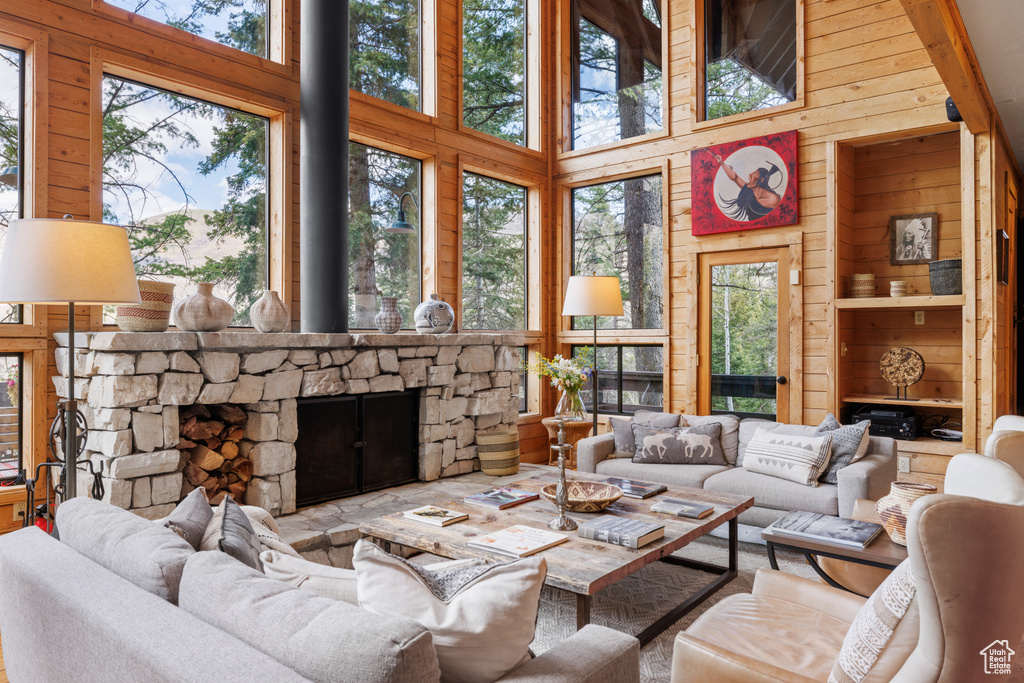 Living room featuring wood walls, a towering ceiling, and a stone fireplace