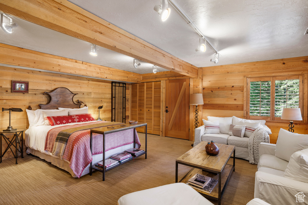 Bedroom featuring rail lighting, wooden walls, and carpet floors