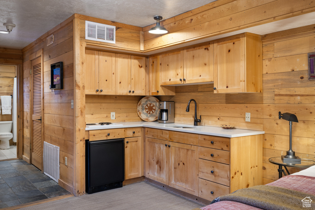 Kitchen featuring wooden walls, a sink, light countertops, and light brown cabinetry