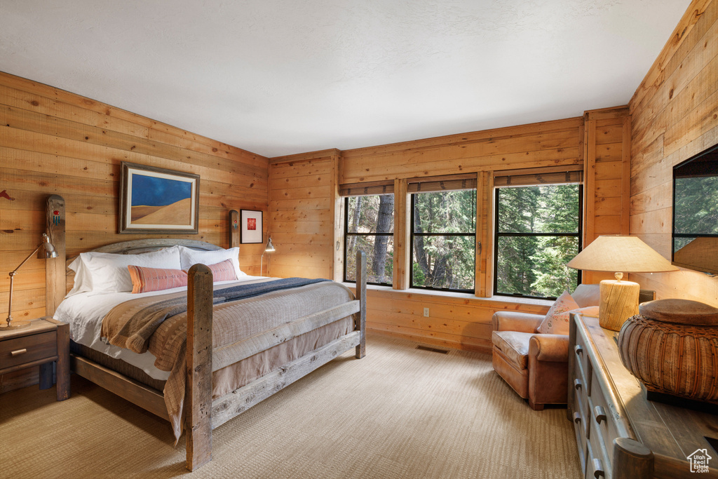 Bedroom with multiple windows, wood walls, and light colored carpet