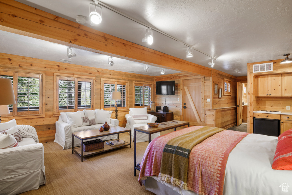 Bedroom featuring wooden walls, rail lighting, and fridge
