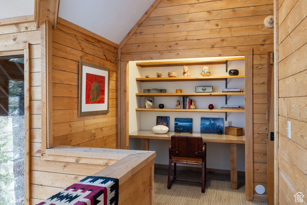 Home office featuring wooden walls and vaulted ceiling
