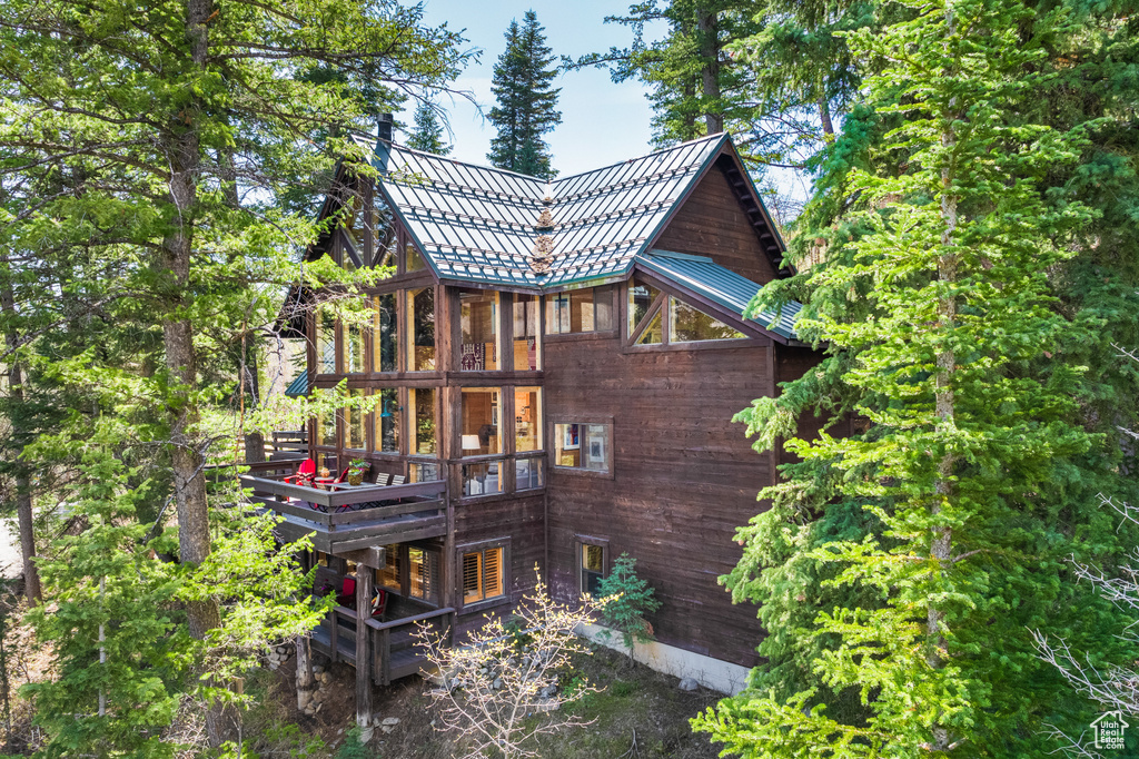 Back of house with metal roof and a deck