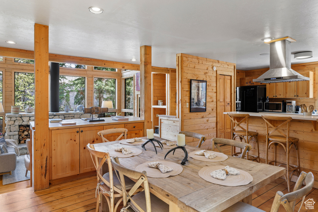 Dining space featuring light wood-type flooring, wood walls, and recessed lighting