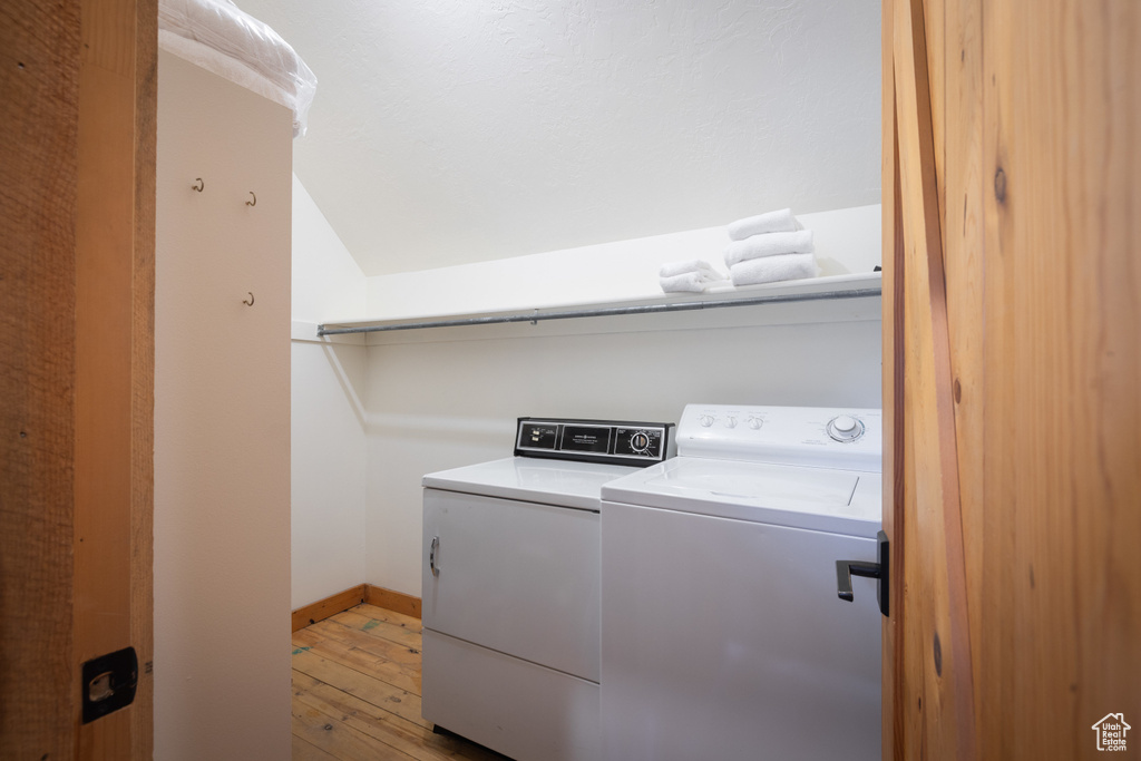 Laundry room featuring washing machine and dryer, light wood-style flooring, and baseboards