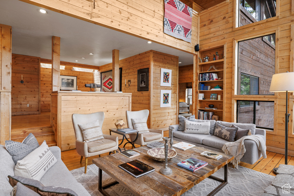 Living area featuring wood walls, a towering ceiling, hardwood / wood-style floors, healthy amount of natural light, and recessed lighting