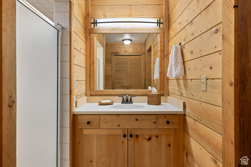Bathroom featuring wood walls, vanity, and a shower stall