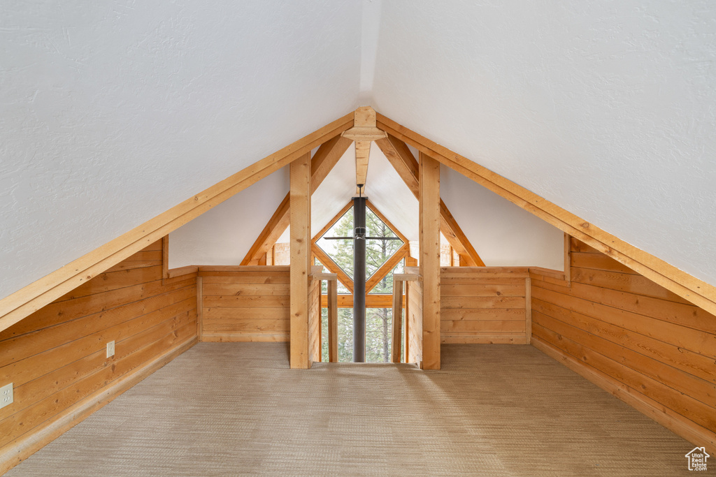 Additional living space with wood walls, lofted ceiling, and carpet