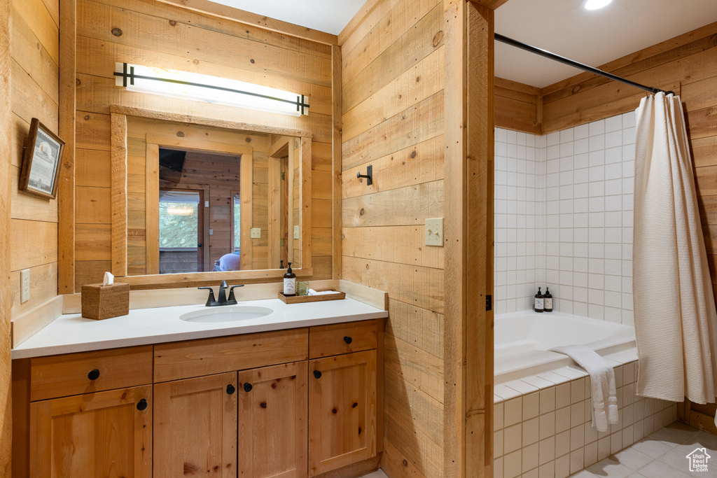 Bathroom featuring wood walls, vanity, tiled shower / bath combo, and tile patterned floors
