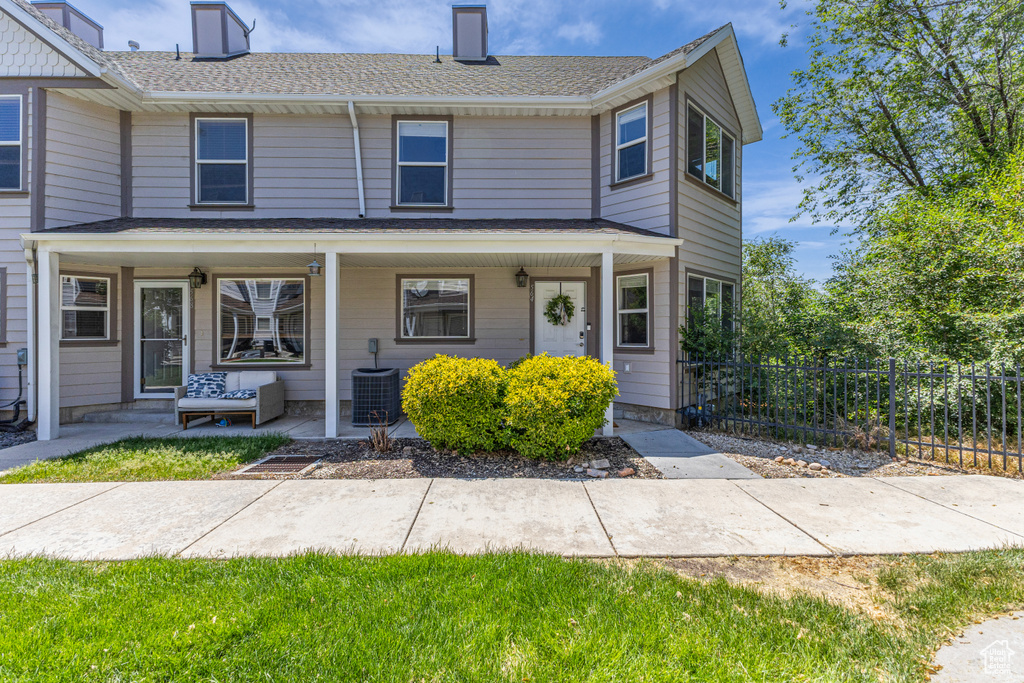 Townhome / multi-family property with a chimney, a porch, and a shingled roof