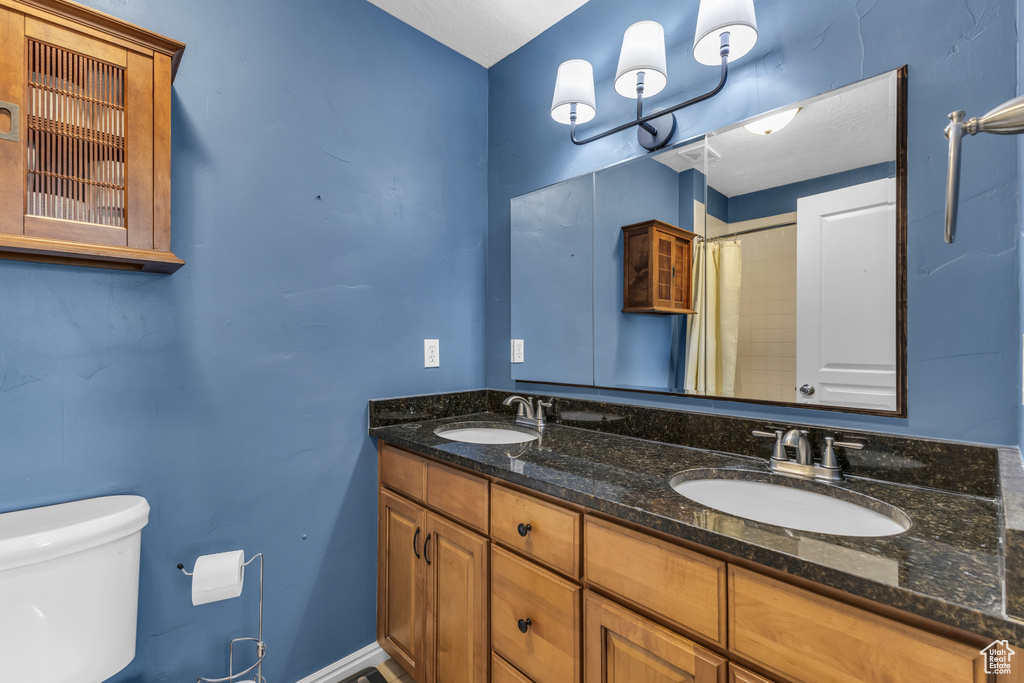 Full bathroom featuring double vanity, toilet, and curtained shower