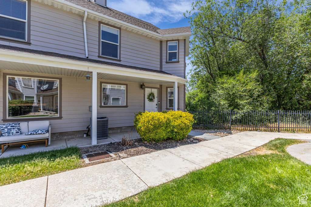View of front of property with central air condition unit, a porch, and roof with shingles