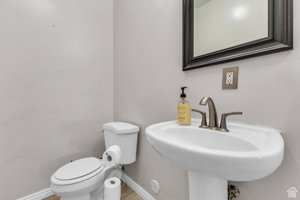 Bathroom with toilet, a sink, baseboards, and tile patterned floors