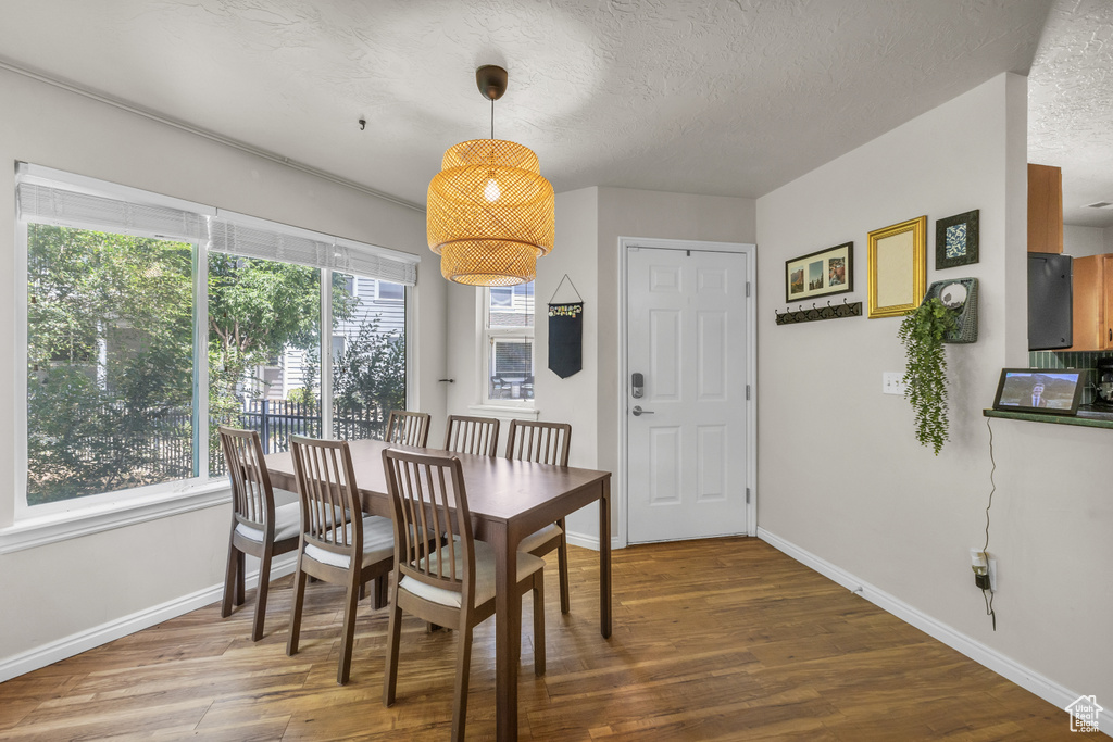 Dining area featuring wood finished floors, baseboards, and a textured ceiling
