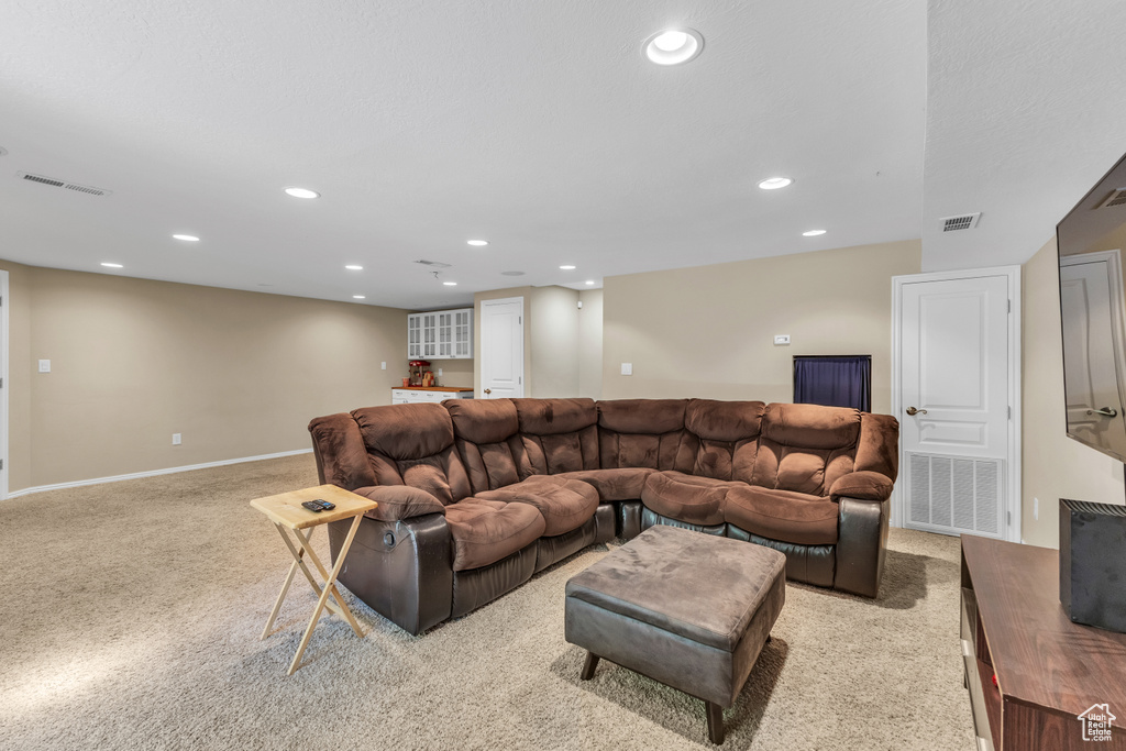 Living area with light colored carpet, recessed lighting, and baseboards