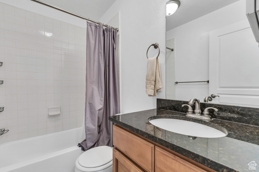 Full bathroom featuring vanity, shower / tub combo with curtain, and toilet