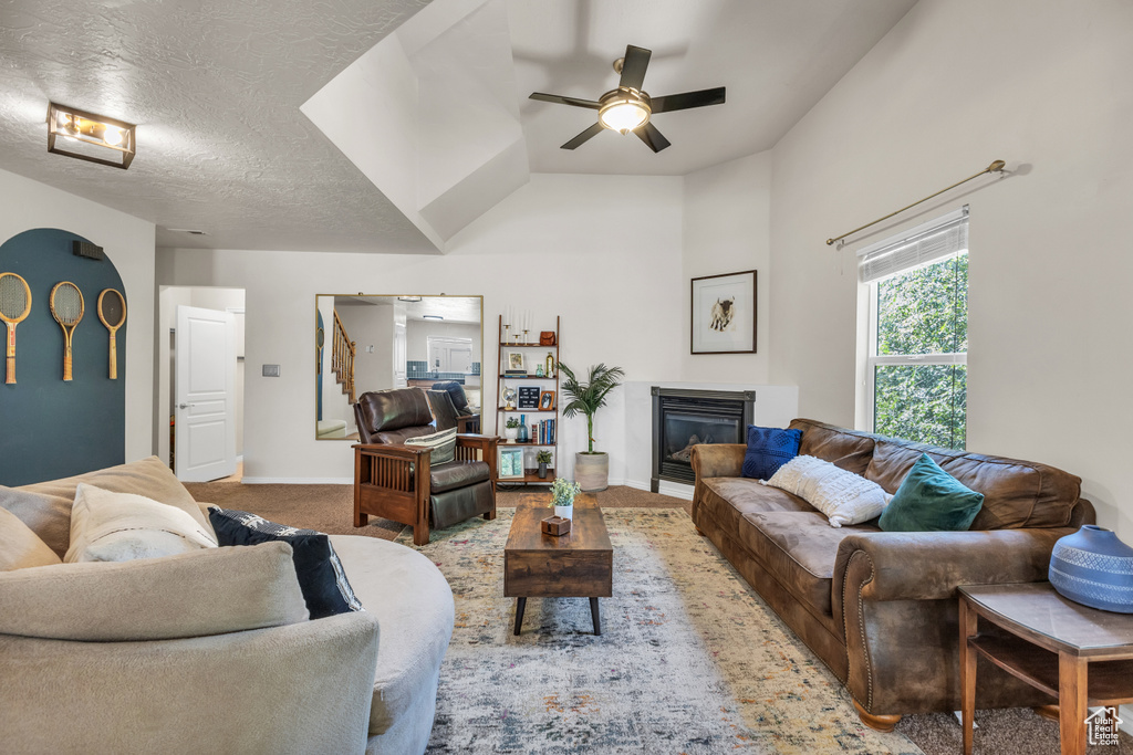 Carpeted living area with a glass covered fireplace, ceiling fan, and baseboards