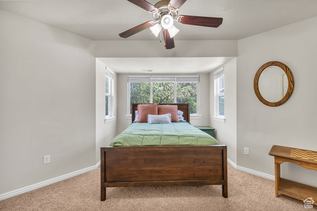 Bedroom with light colored carpet, baseboards, and a ceiling fan