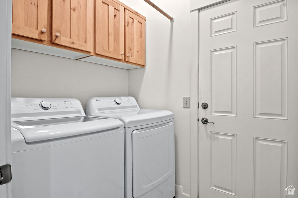 Washroom featuring washer and clothes dryer and cabinet space