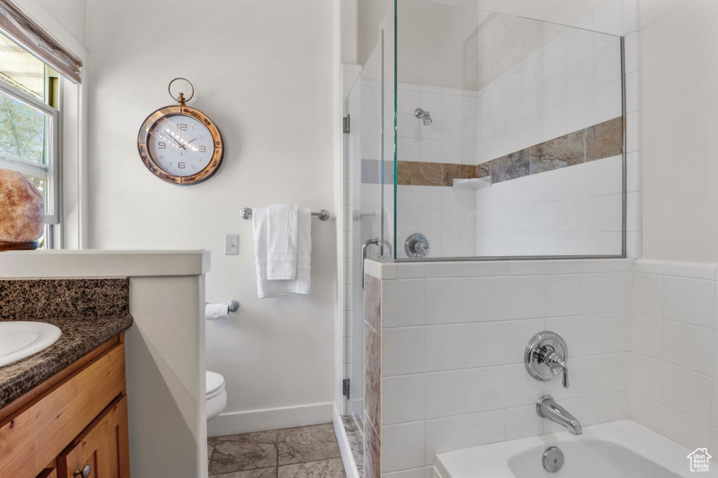 Bathroom with toilet, vanity, baseboards, and shower / tub combination