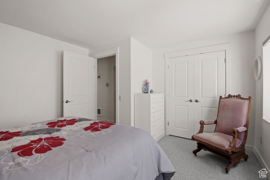 Bedroom with light colored carpet and a closet