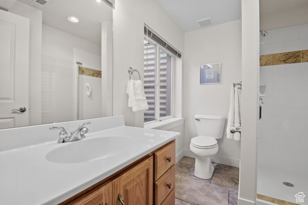 Bathroom featuring a shower stall, vanity, toilet, and baseboards