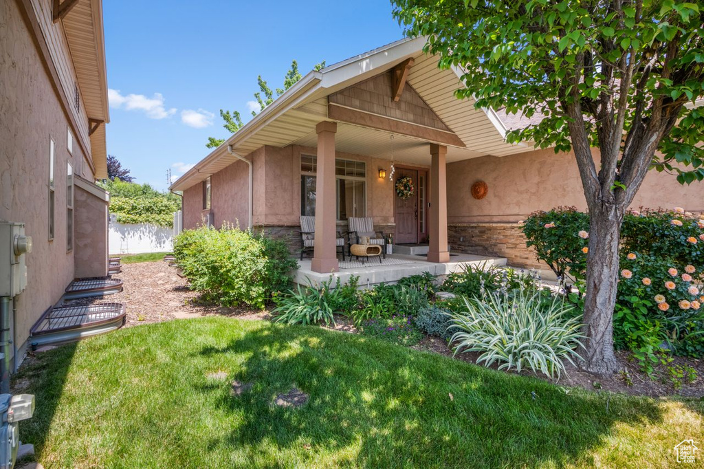 Property entrance featuring covered porch, stucco siding, and stone siding