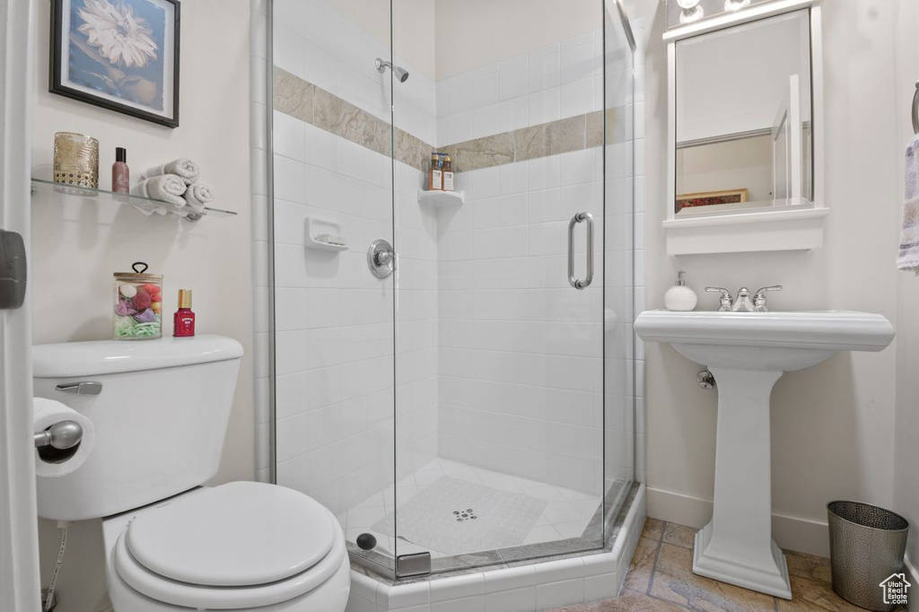 Full bath featuring toilet, a shower stall, and baseboards