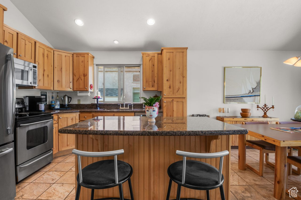 Kitchen featuring stainless steel appliances, a breakfast bar area, a center island, light tile patterned flooring, and recessed lighting