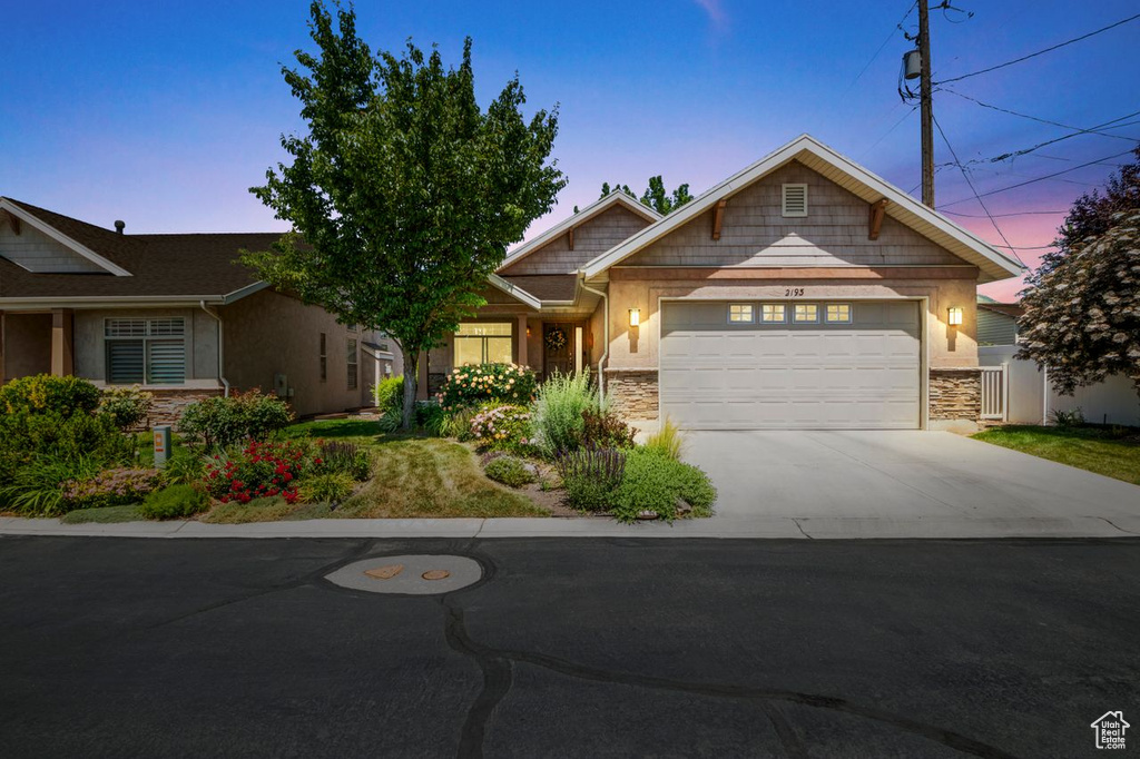 Craftsman-style house featuring stone siding, a garage, and driveway