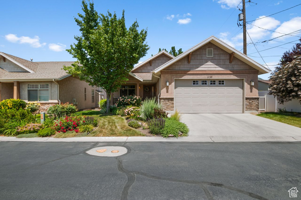 View of front of home featuring stone siding, an attached garage, and concrete driveway