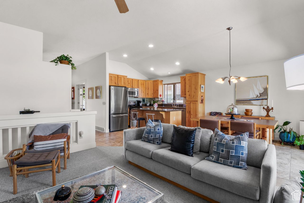 Living room featuring vaulted ceiling, recessed lighting, a chandelier, ceiling fan, and light carpet