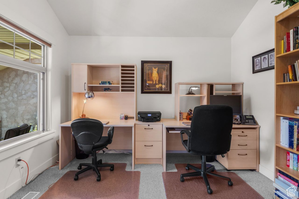 Home office with light colored carpet and vaulted ceiling