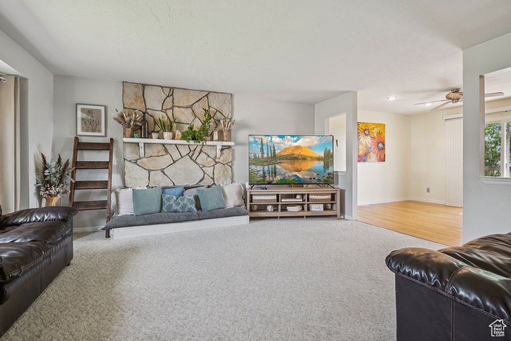 Carpeted living room featuring ceiling fan and baseboards