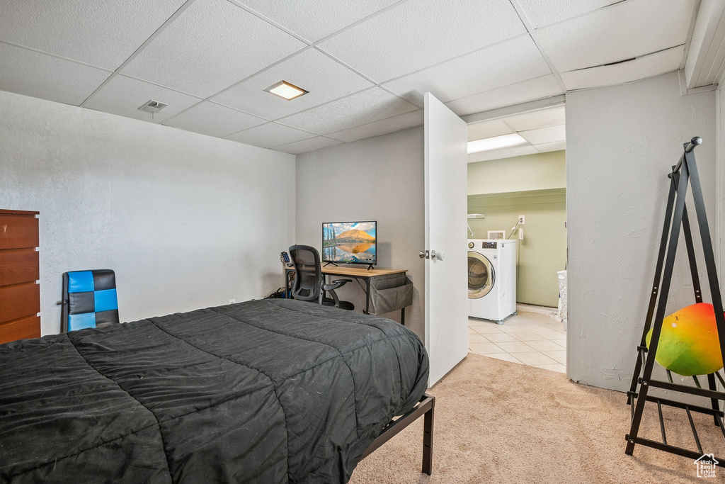 Bedroom featuring washer / dryer, a drop ceiling, carpet, and tile patterned flooring