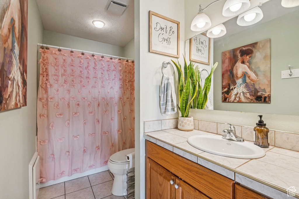 Full bathroom with toilet, vanity, tile patterned flooring, a textured ceiling, and shower / tub combo
